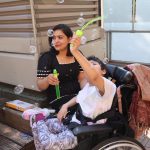 A child in a wheelchair and a Support Worker play with bubbles outdoors during the Special People Open Day.